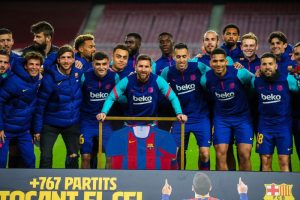 Leo Messi ao lado dos seus companheiros e da camisa autografada por eles.
